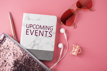 Upcoming events concept with fashion glitter bag, sunglasses, earphone and pen on pink backgroundの写真素材