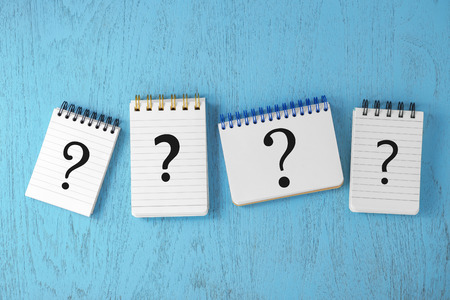 Question marks on notepads on blue wooden desk, faq concept, top viewの写真素材