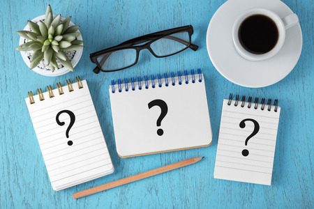 Faq concept with question marks on notepads on blue wooden table, top viewの写真素材