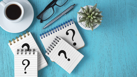 Faq concept with question marks on notepads, pen and coffee cup on blue wooden background, top view