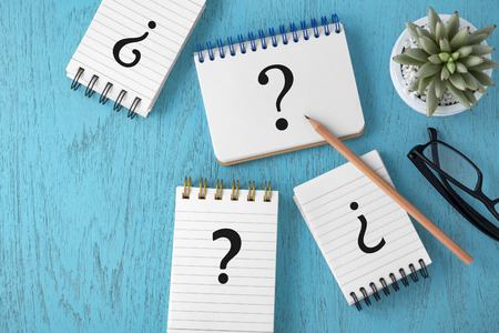 Question marks on notepads on blue wooden background, variety of questions, faq concept, top viewの写真素材