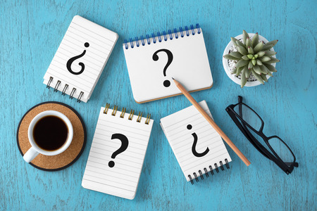 Variety of question marks on notepads with coffee cup on blue wooden desk, top viewの写真素材