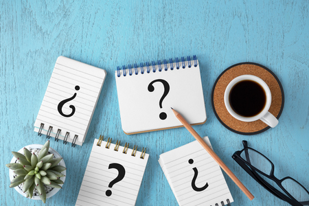 Variety of question marks on notepads on blue wooden background, faq concept, top viewの写真素材