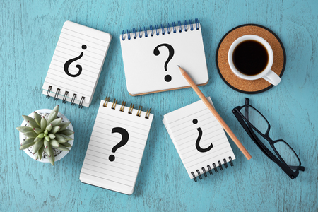 Question marks on notepads on blue wooden desk, variety of questions, faq concept, top viewの写真素材