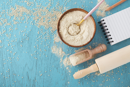 Gluten free baking background with quinoa flour in bowl and quinoa seeds on blue wooden tableの写真素材