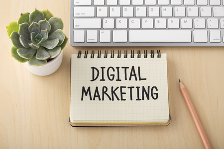 Digital marketing word on notebook with computer keyboard on wooden deskの写真素材