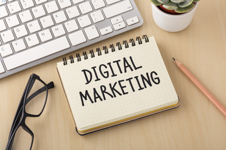 Digital marketing word on notebook with computer keyboard and pencil on wooden deskの写真素材