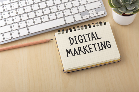 Digital marketing word on notebook with computer keyboard and pencil on wooden desk with spaceの写真素材