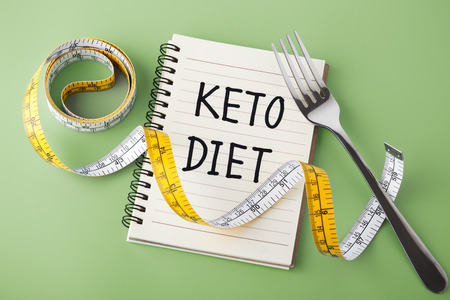 Keto diet concept with measuring tape and fork on green backgroundの写真素材