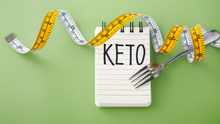 Keto word on notebook with fork and measuring tape on green background, ketogenic conceptの写真素材