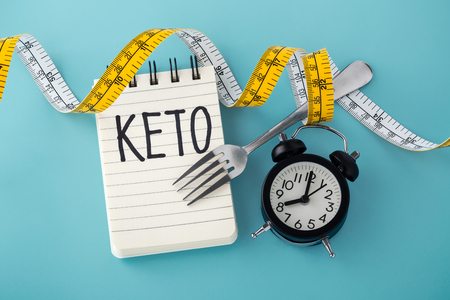 Keto word with clock, fork and measuring tape around on blue background, top viewの写真素材