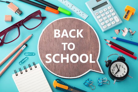 Back to school on wooden speech bubble sign with school supplies on blue backgroundの写真素材