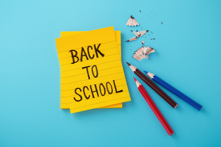 Back to school word on yellow note with color pencils on blue backgroundの写真素材