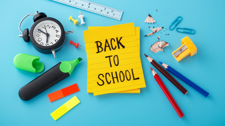Back to school word on yellow note with clock and school suppliesの写真素材