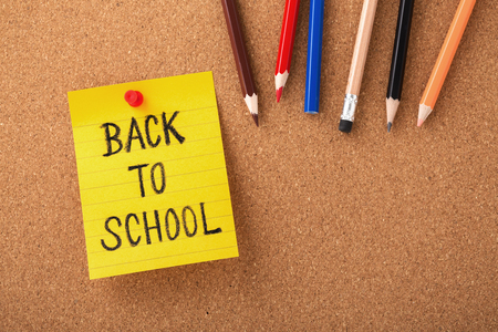 Back to school on yellow note with color pencils on cork board background with copy spaceの写真素材