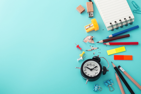 School supplies with clock on blue background with copy space, back to school conceptの写真素材