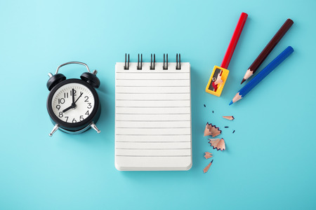 Notebook with clock and pencil color on blue backgroundの写真素材