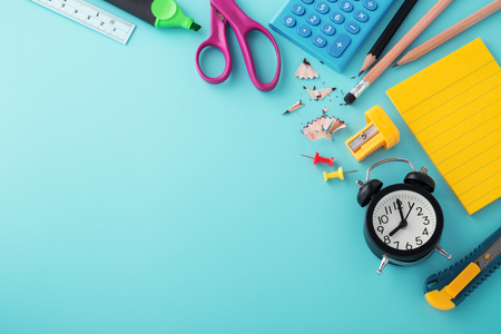 School supplies with clock on blue background with copy space, back to school conceptの写真素材