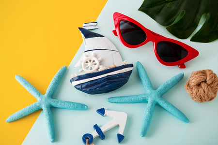 Summer holiday travel concept with red sunglasses on yellow and blue background, top viewの写真素材