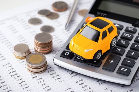 Car on calculator with coins on financial statementの写真素材