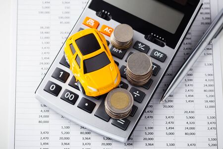 Car and coins on calculator with pen on financial statementの写真素材