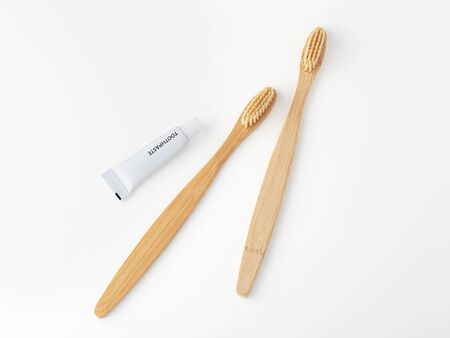Bamboo toothbrushes with travel sized toothpaste on white backgroundの写真素材