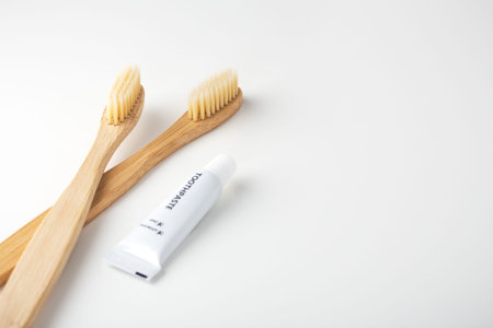 Bamboo toothbrushes and toothpaste on white background with space
