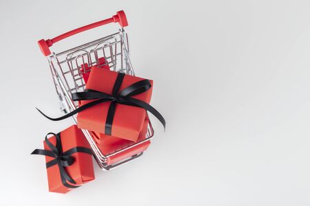 Red gift box with black bow in shopping cart, black friday sale background, top viewの写真素材