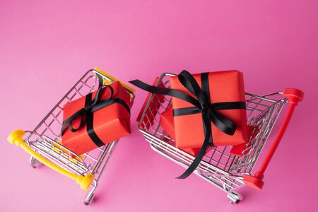 Shopping cart with red box on pink background, black friday saleの写真素材