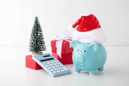 Piggy bank wearing christmas hat with calculator and christmas decor, christmas saving conceptの写真素材