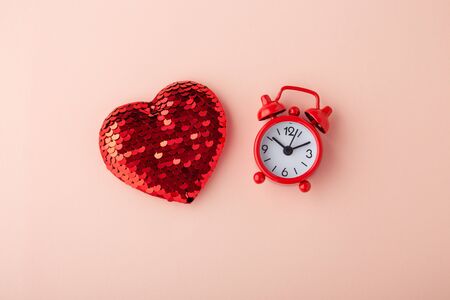 Glitter heart with red clock on pink background, flat layの写真素材