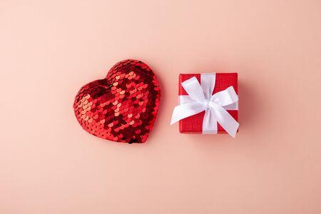 Glitter heart and red gift box with white bow on pink background, valentines day, flat layの写真素材