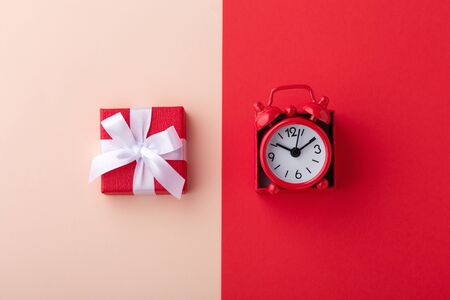 Gift box and red clock on pink and red background, flat layの写真素材