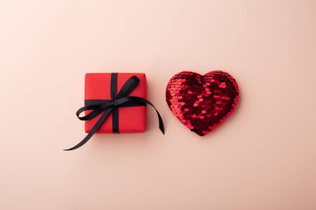 Red gift box and glitter heart on pink background, flat layの写真素材