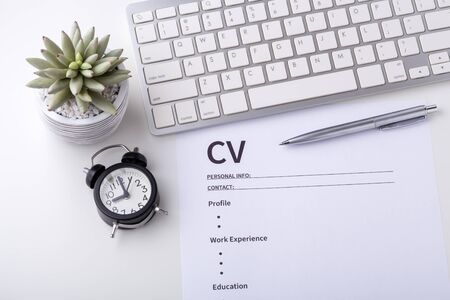 CV with pen, computer keyboard and clock on white deskの写真素材