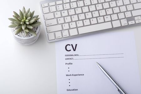 CV with pen and computer keyboard on white tableの写真素材