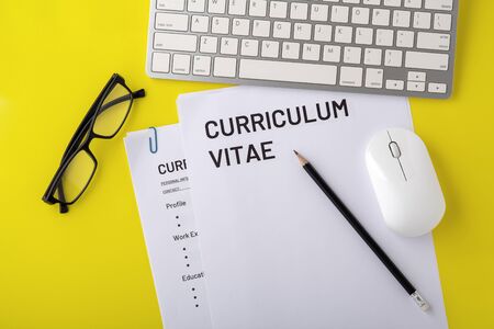 CV, curriculum vitae with computer keyboard, mouse, pencil on yellow desk, top viewの写真素材
