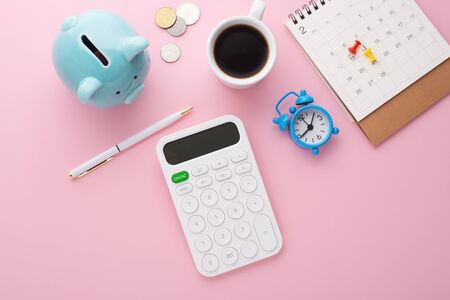 Calculator, calendar and piggy bank on pink background, top viewの写真素材