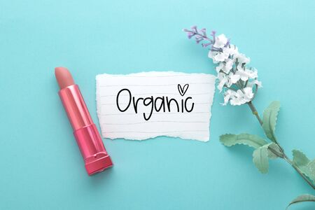 Lipstick and flower with organic text on paper on blue background, top viewの写真素材
