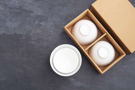 Ceramic bowl in paper gift box package mockup on black stone background, top view with copy spaceの写真素材