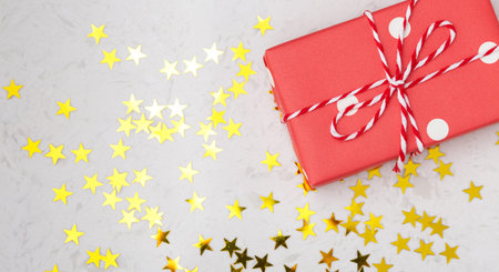 Christmas background with red gift box and gold star decoration on marble table