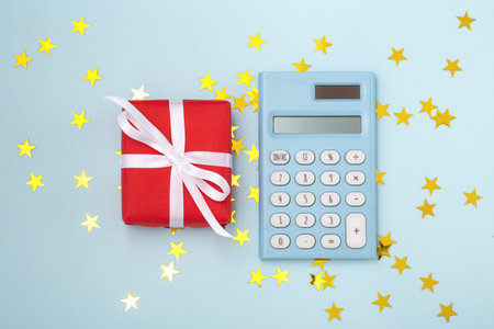Christmas gift box with calculator on blue background, christmas budget concept