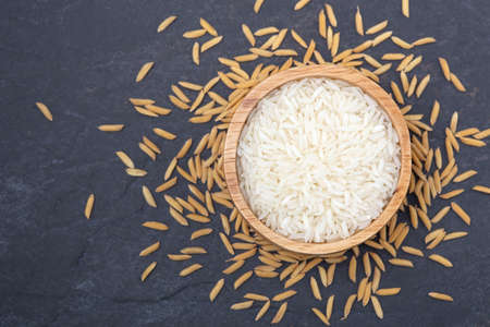 Jasmine rice in wooden scoop with rice paddyの写真素材