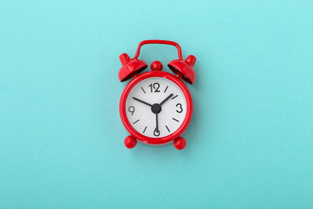Red clock on blue background, flat lay