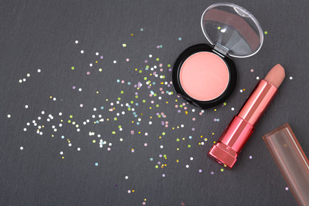 Makeup with lipstick and blush on dark background with glitter, top viewの写真素材