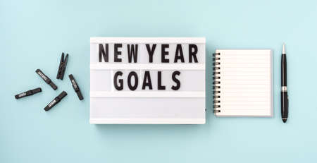 New year goals text on lightbox with notebook and pen on blue backgroundの写真素材