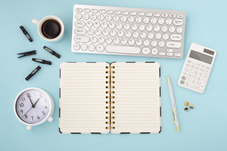 Open notebook with office accessories on blue background, flatlay