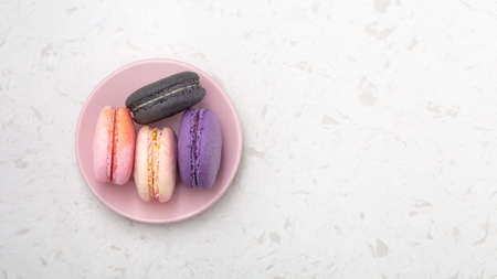 Macaron on pink plate on white marble background, top view with copy spaceの写真素材