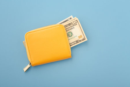 Money in yellow wallet on blue background, flatlay