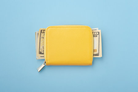 Money in yellow wallet on blue background, flatlayの写真素材